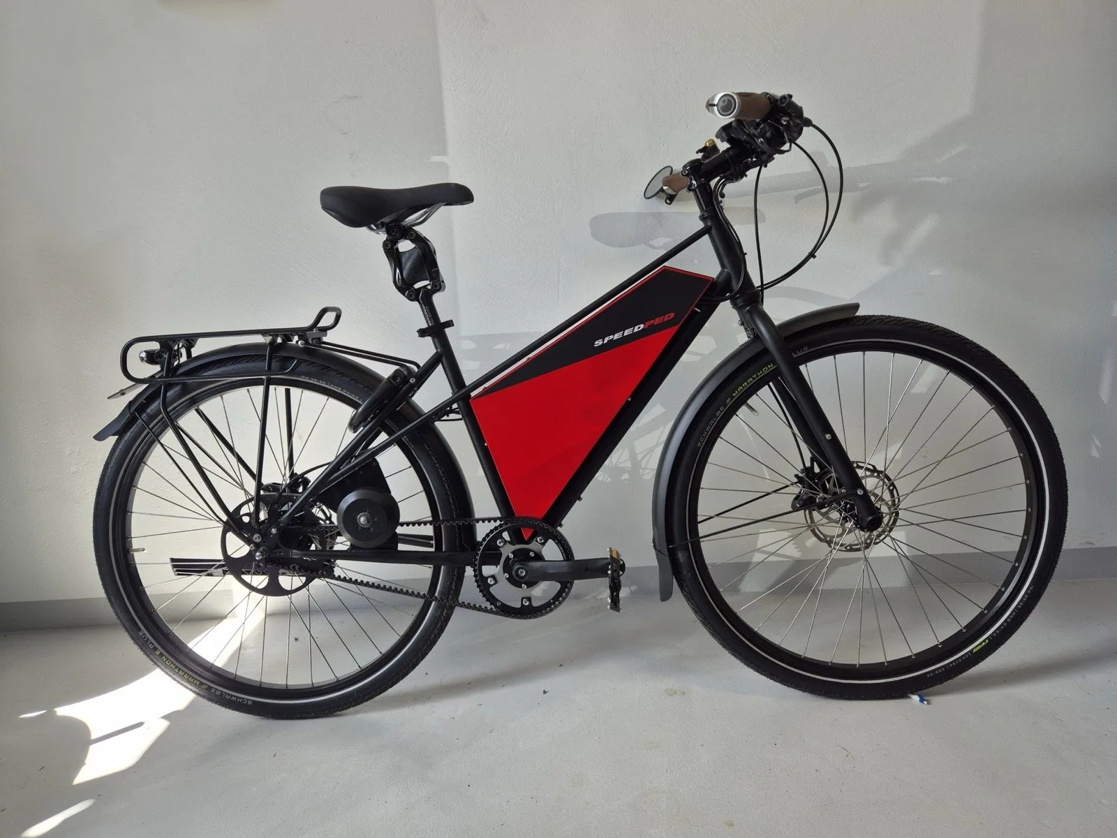 Vélo électrique SpeedPed noir et rouge de profil — porte-bagages, garde-boue et freins à disque